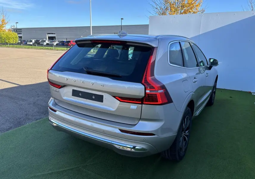 Vue 3/4 arrière droite d'un Volvo XC60 argent crépuscule métal avec feux arrière LED et jantes alliage noires.