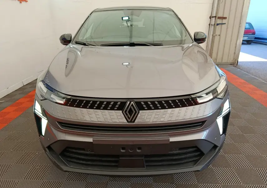 Vue frontale d'un Renault Captur gris foncé 2025 avec phares LED allumés et calandre moderne distinctive.