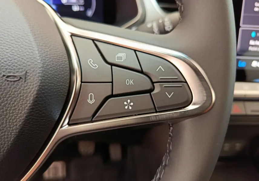 Gros plan sur les commandes multifonctions à droite du volant noir du Renault Captur gris foncé 2025 avec écran tactile visible.