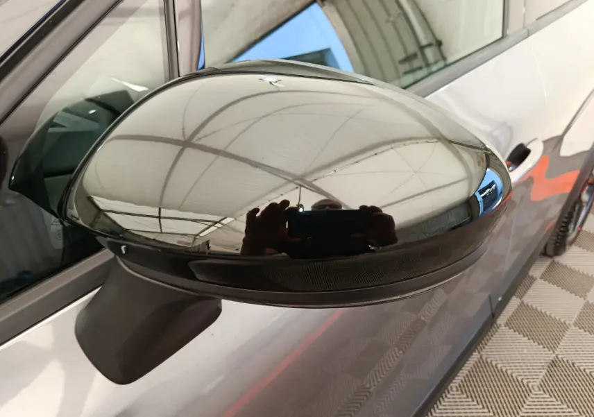 Rétroviseur côté gauche gris foncé du Renault Captur 2025 avec carrosserie et poignée de porte visibles en arrière-plan.