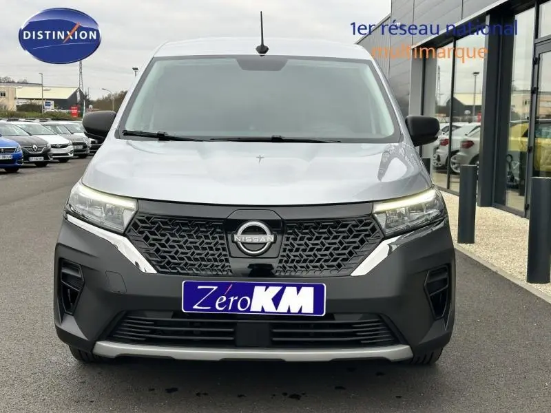 Vue frontale d'un Nissan Townstar gris 2024 avec calandre noire et plaque "Zéro KM" visible sur un parking.