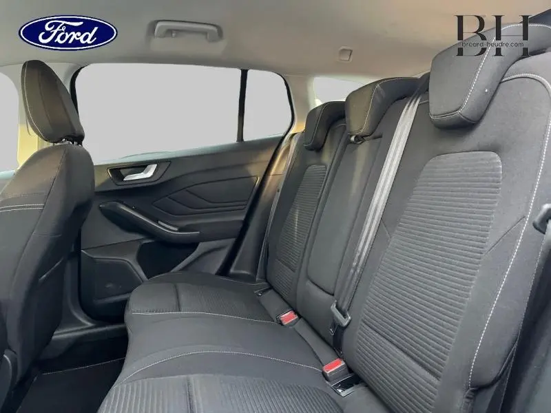 Vue intérieure arrière côté gauche du Ford Focus SW 2024 avec sièges tissu noir et ceintures grises.