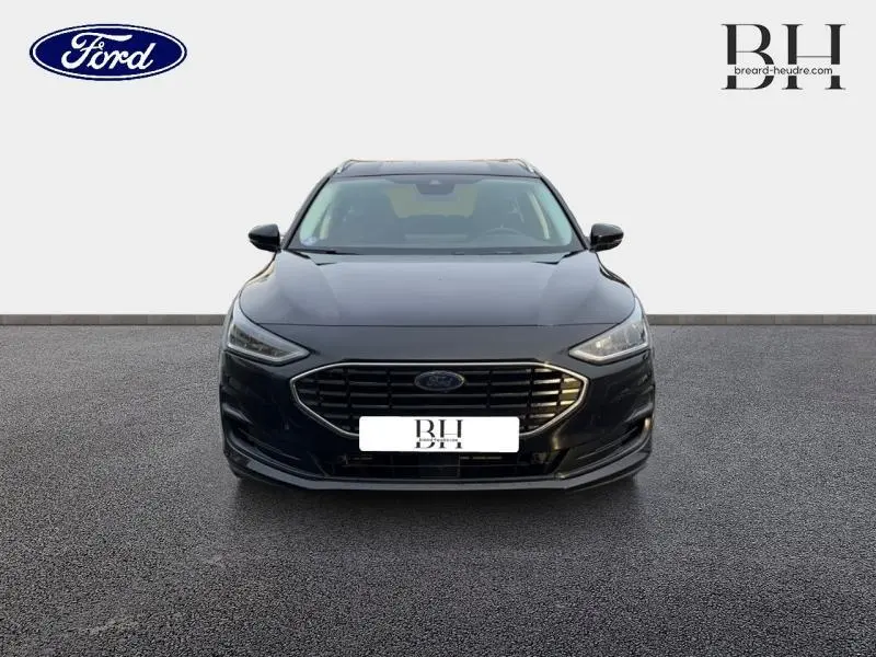 Vue frontale d'une Ford Focus SW 2024 noir Agate métallisé avec calandre chromée et phares LED allumés.