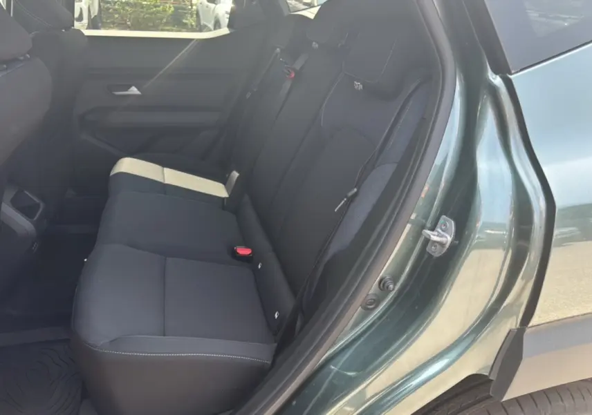 Vue côté droit sur la banquette arrière noire du Dacia Duster HEV 140 Journey Plus vert cèdre 2025 avec porte ouverte.