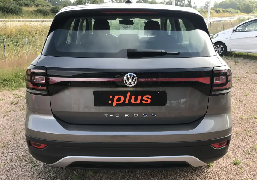 Vue arrière d'un Volkswagen T-Cross gris limestone 2020 avec feux arrière noirs et logo VW centré.
