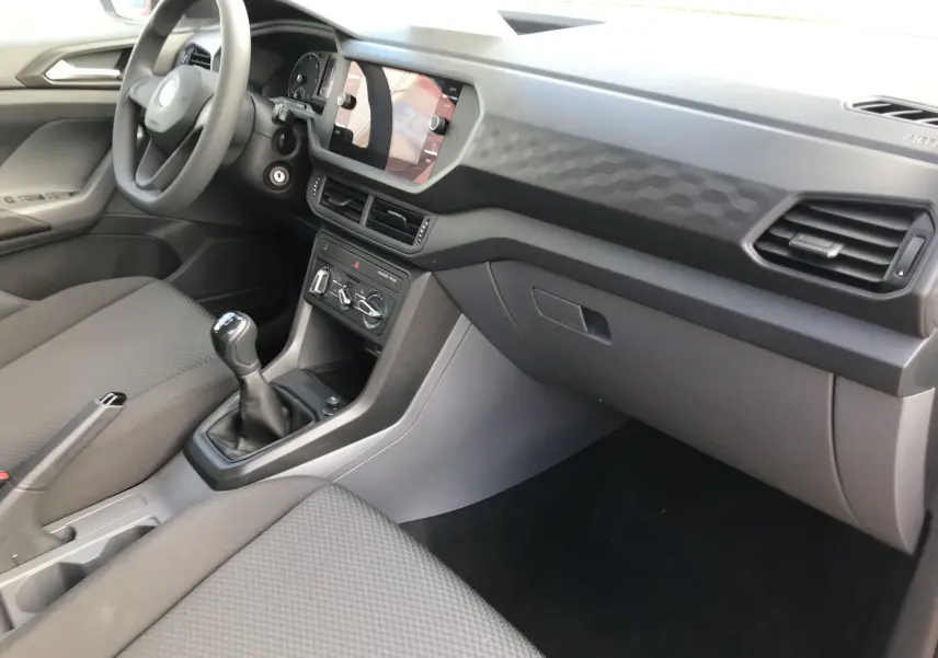 Intérieur côté passager du Volkswagen T-Cross 2020 gris Limestone, avec tableau de bord texturé et levier de vitesse manuel.