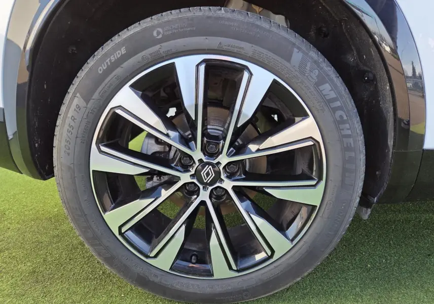 Gros plan sur la jante alliage 19 pouces noire et diamantée du Renault Austral blanc nacré avec toit noir.