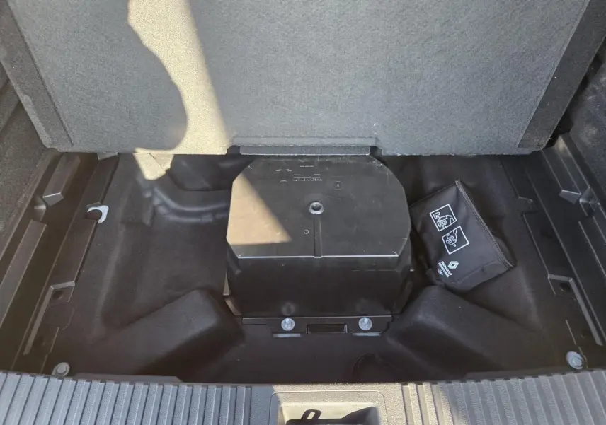 Vue plongeante sur le coffre du Renault Austral blanc nacré, montrant le rangement sous plancher avec trousse de secours.