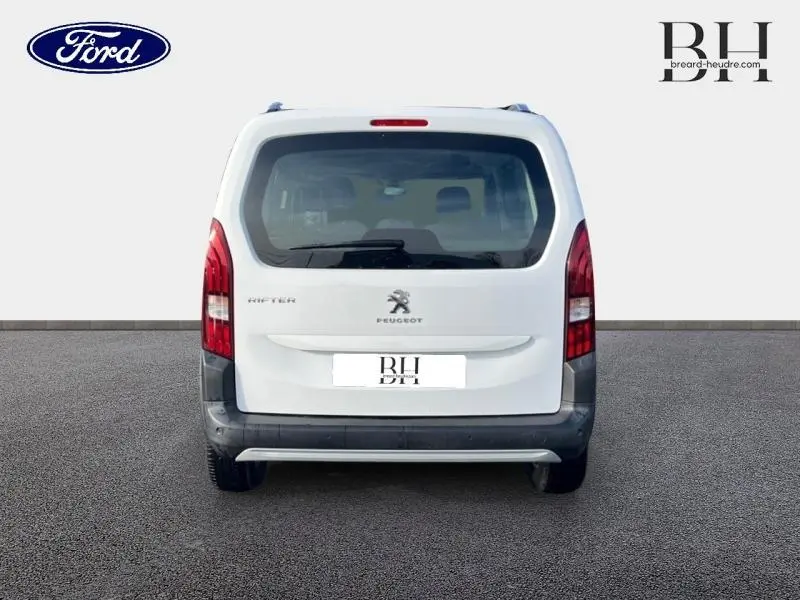 Vue arrière d'un Peugeot Rifter blanc avec feux arrière verticaux et logo lion central visible.