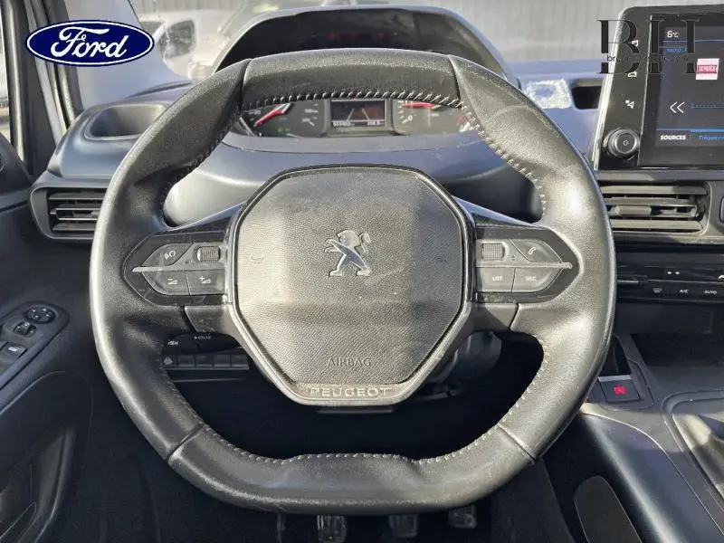 Vue rapprochée du volant cuir noir du Peugeot Rifter 2020 avec commandes intégrées et tableau de bord en arrière-plan.