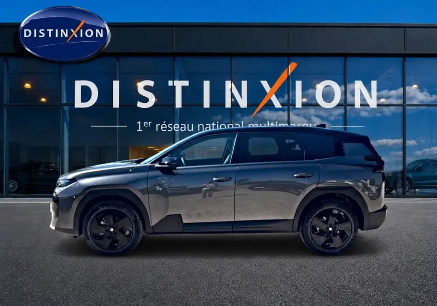 Profil droit du Citroën C5 Aircross gris platinium avec toit noir et jantes alliage noires devant une vitrine Distinxion.