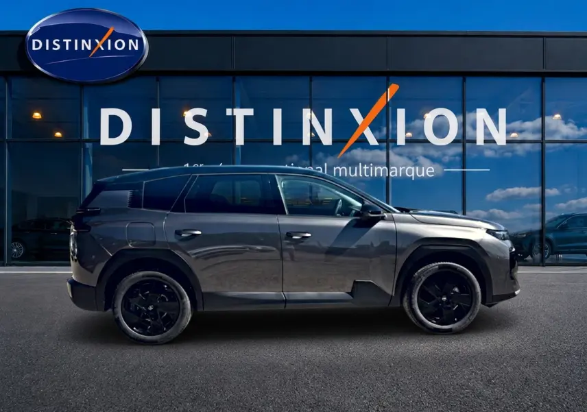 Profil côté gauche du Citroën C5 Aircross gris platinium avec toit noir et jantes alliage noires devant une vitrine Distinxion.
