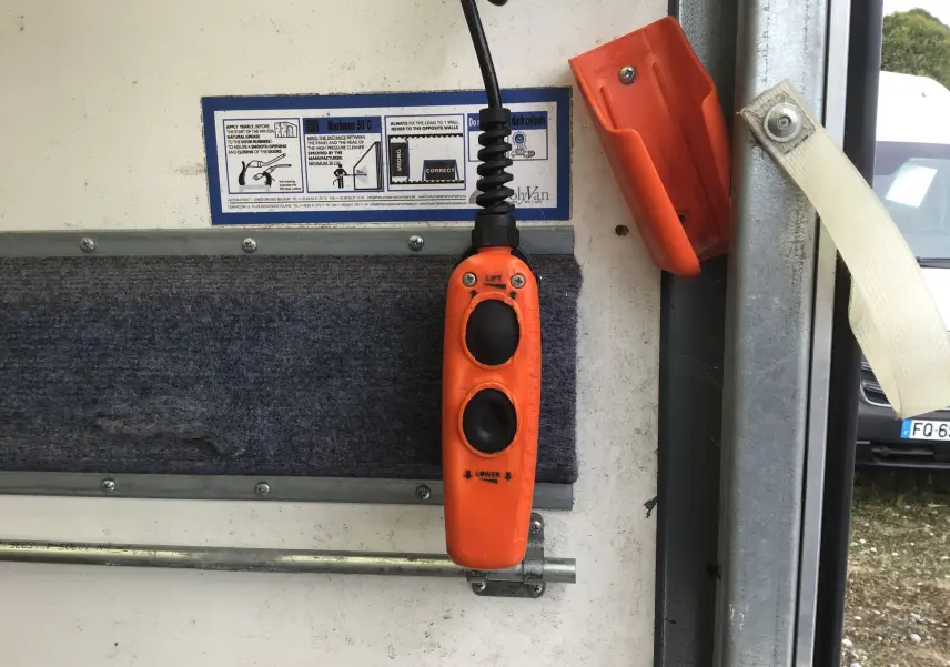 Télécommande orange du hayon arrière du camion Iveco Daily blanc, vue intérieure côté droit de la caisse.