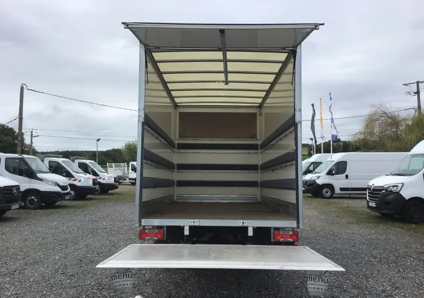 Vue arrière d’un Iveco Daily blanc 2022 avec caisse ouverte de 20m3 et hayon élévateur déployé sur parking