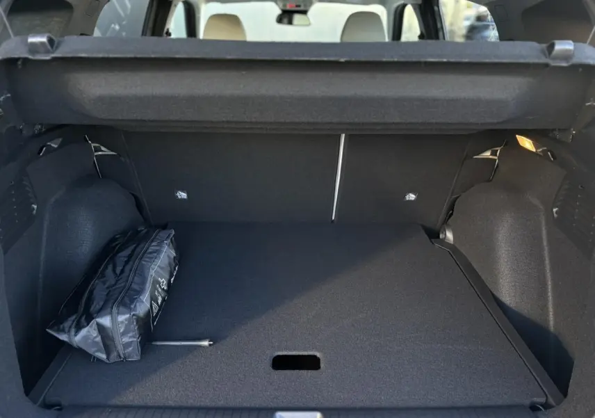 Coffre ouvert d'une Citroën C3 Aircross gris Mercury, montrant un rangement plat avec trousse de secours noire.