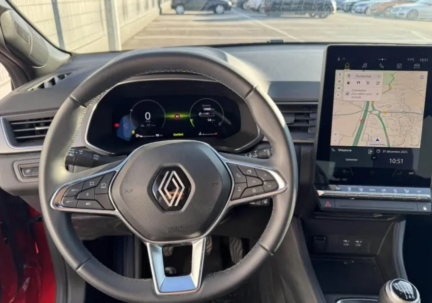 Vue intérieure centrée sur le volant Renault d’un Captur II 2025, avec tableau de bord numérique et écran tactile GPS.
