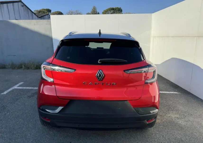 Vue arrière du Renault Captur II rouge flamme avec toit noir, mettant en valeur ses feux LED et son logo central.
