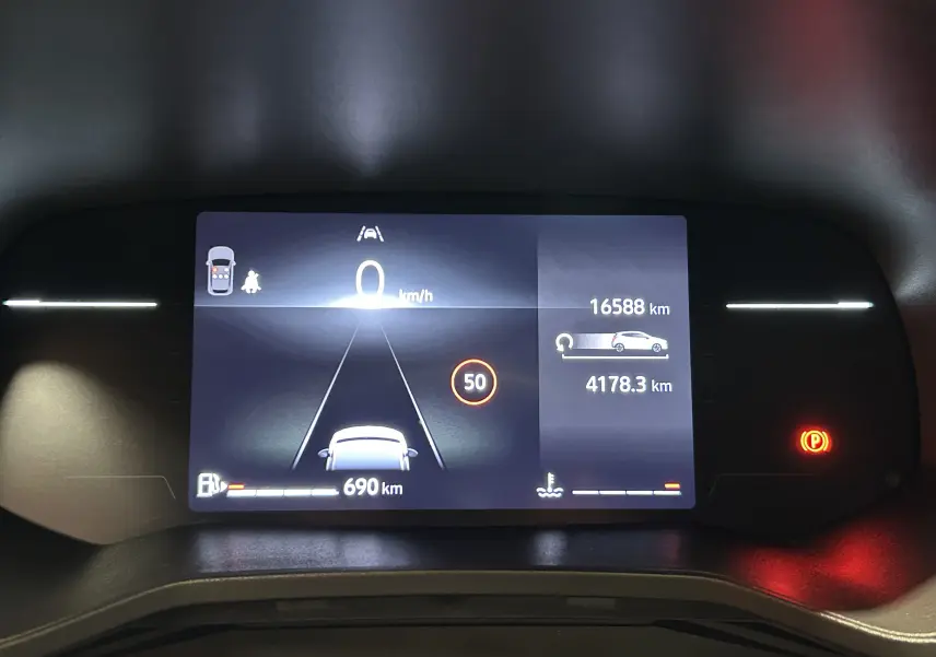 Vue rapprochée du tableau de bord numérique de la Renault Clio V blanc, affichant la vitesse à 0 km/h et l'autonomie restante.