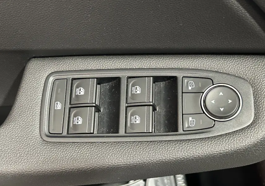 Panneau de commandes des vitres électriques et réglages des rétroviseurs dans l’habitacle d’une Renault Clio V blanche.