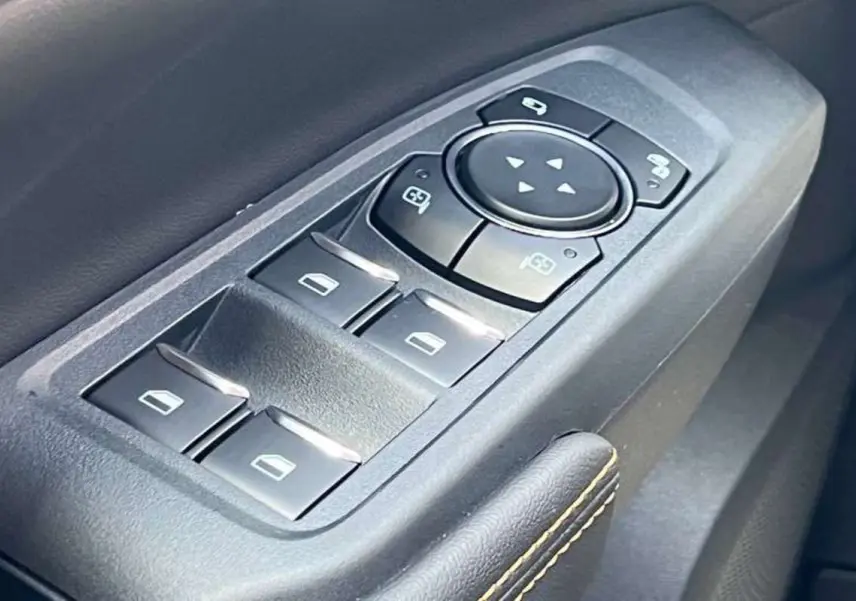 Gros plan sur les commandes des vitres électriques et rétroviseurs du côté conducteur du Ford Ranger Wildtrak Plus noir agate.