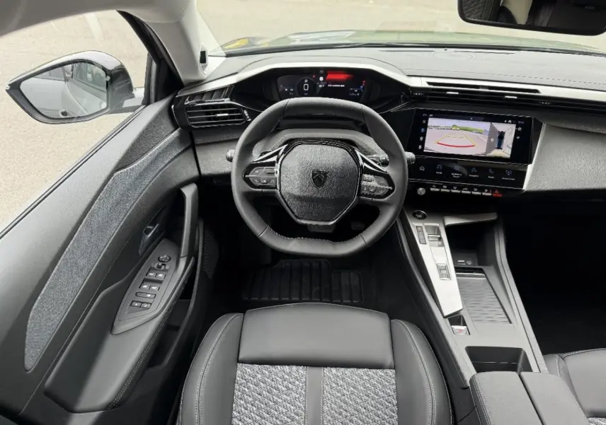 Vue intérieure de face du poste de conduite de la Peugeot 308 2026, avec volant compact et écran tactile affichant la caméra de recul.
