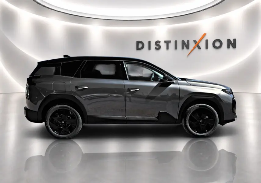 Vue latérale droite d'un Citroën C5 Aircross gris platinium avec toit noir et jantes alliage noires dans un showroom.