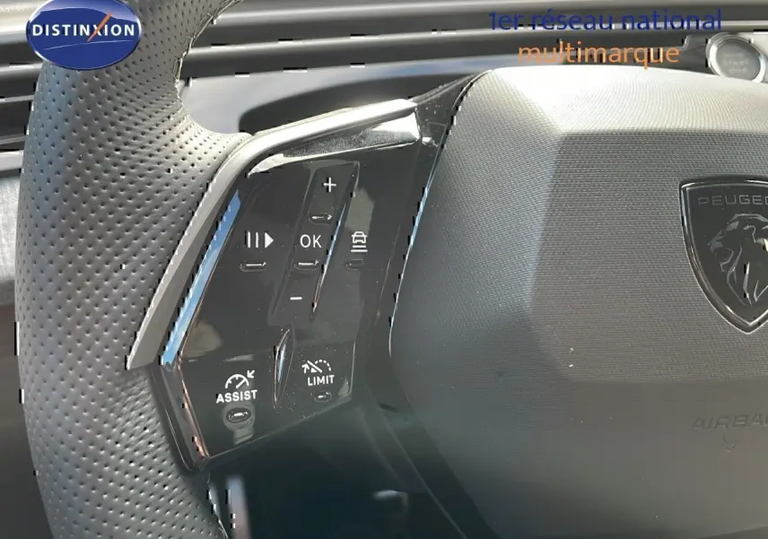 Gros plan sur les commandes multifonctions à gauche du volant perforé du Peugeot 3008 hybride bleu Ingaro métal.