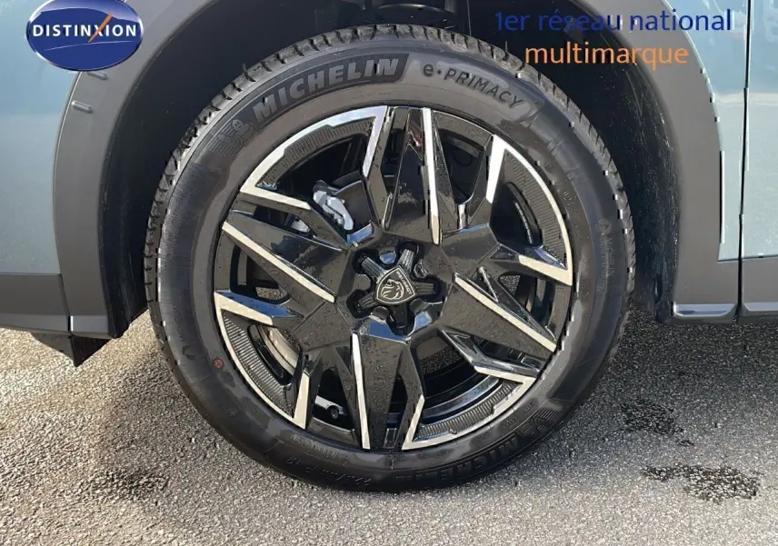 Gros plan sur la roue avant gauche d'un Peugeot 3008 bleu Ingaro métal avec jante alliage noire et argentée.