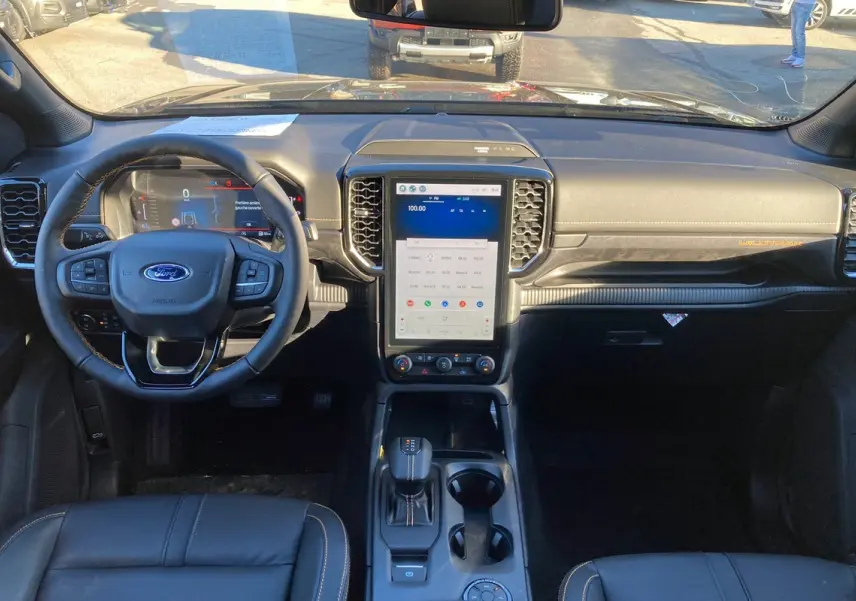 Vue frontale de l'intérieur du Ford Ranger 2025 bleu lightning, tableau de bord avec écran tactile vertical et volant multifonction.