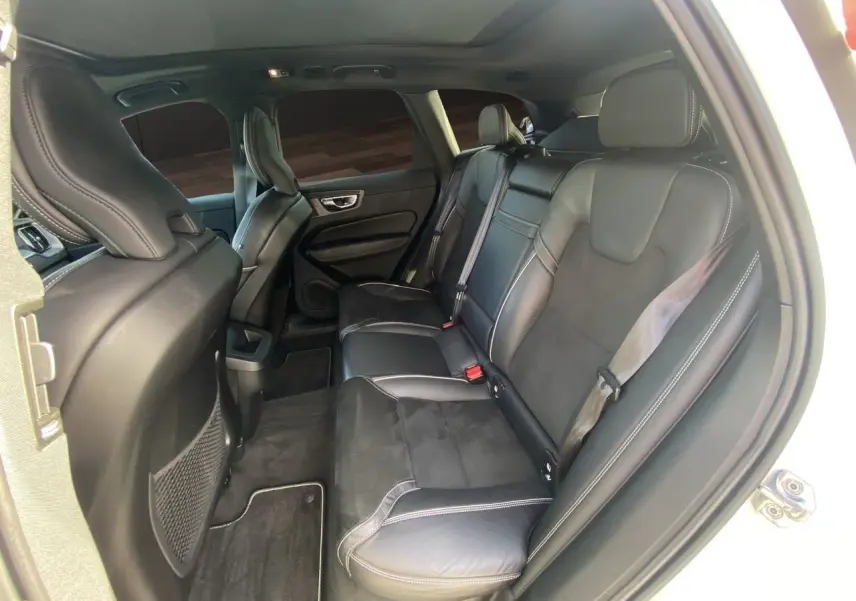 Vue intérieure arrière droite du Volvo XC60 blanc 2019, sièges en cuir noir avec surpiqûres contrastées.