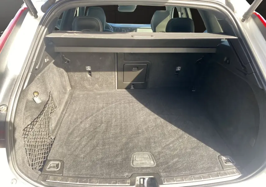 Coffre ouvert d'un Volvo XC60 blanc 2019, vue arrière montrant l'espace de chargement et la plage arrière noire.