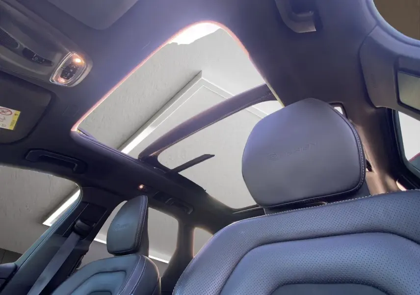 Vue intérieure du toit ouvrant panoramique et sièges avant en cuir noir embossé R-DESIGN du Volvo XC60 blanc 2019.