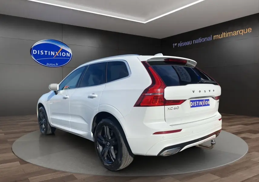 Vue 3/4 arrière droite du Volvo XC60 blanc 2019 avec jantes noires et feux arrière LED distinctifs.