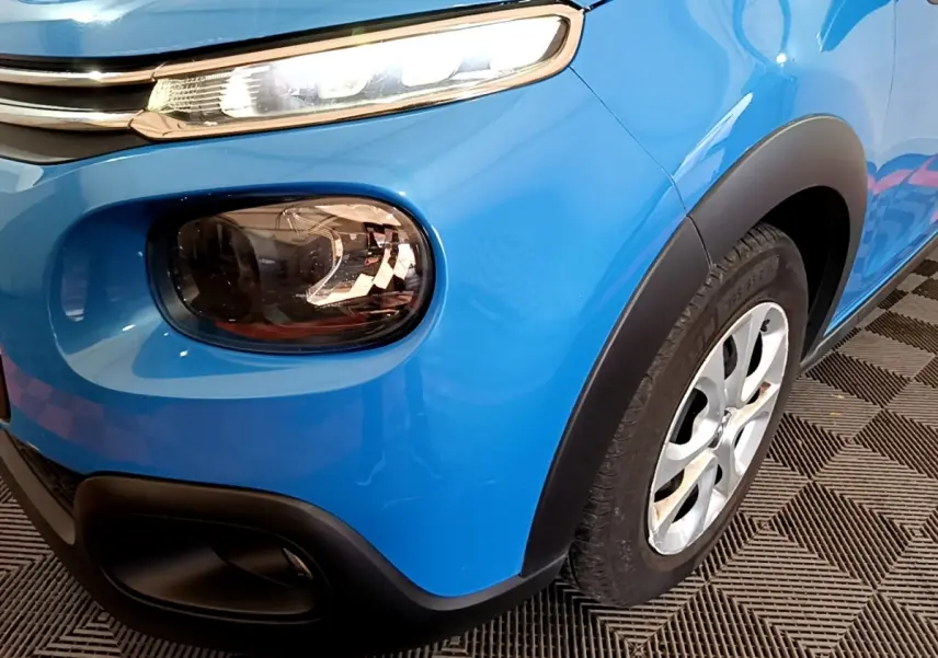 Gros plan sur l'avant droit bleu vif de la Citroën C3 2017, mettant en valeur ses phares distinctifs et la roue.