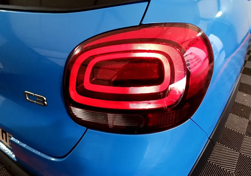 Gros plan sur le feu arrière droit rouge et la carrosserie bleue d'une Citroën C3 2017, version BlueHDi Feel Business.