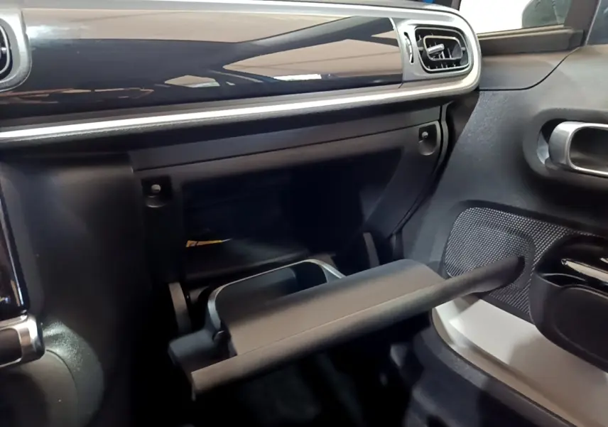 Intérieur de la Citroën C3 2017, vue du coffre à gants ouvert côté passager avec finition noire et détails argentés.