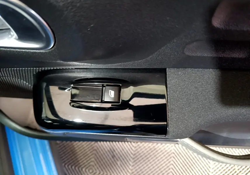 Bouton de commande de lève-vitre sur la porte côté conducteur d'une Citroën C3 bleu 2017, intérieur noir.