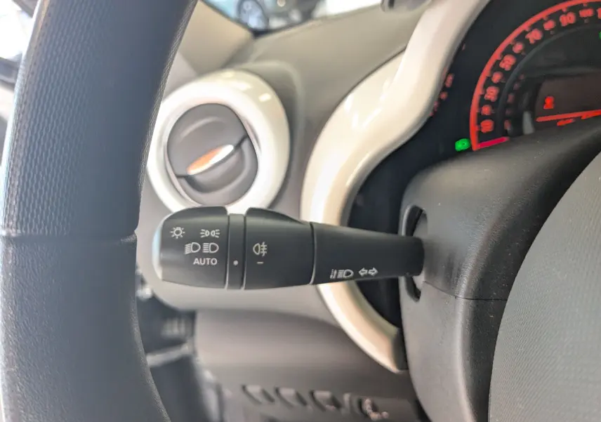 Gros plan sur la commande des phares et clignotants à gauche du volant dans une Renault Twingo III gris cassiopée.