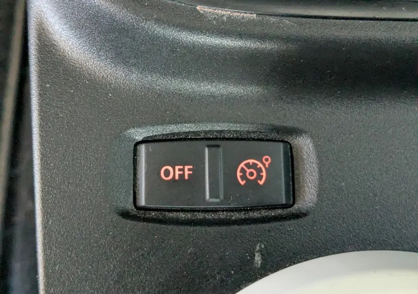 Gros plan sur le bouton de désactivation du régulateur de vitesse dans une Renault Twingo III gris Cassiopée de 2021.