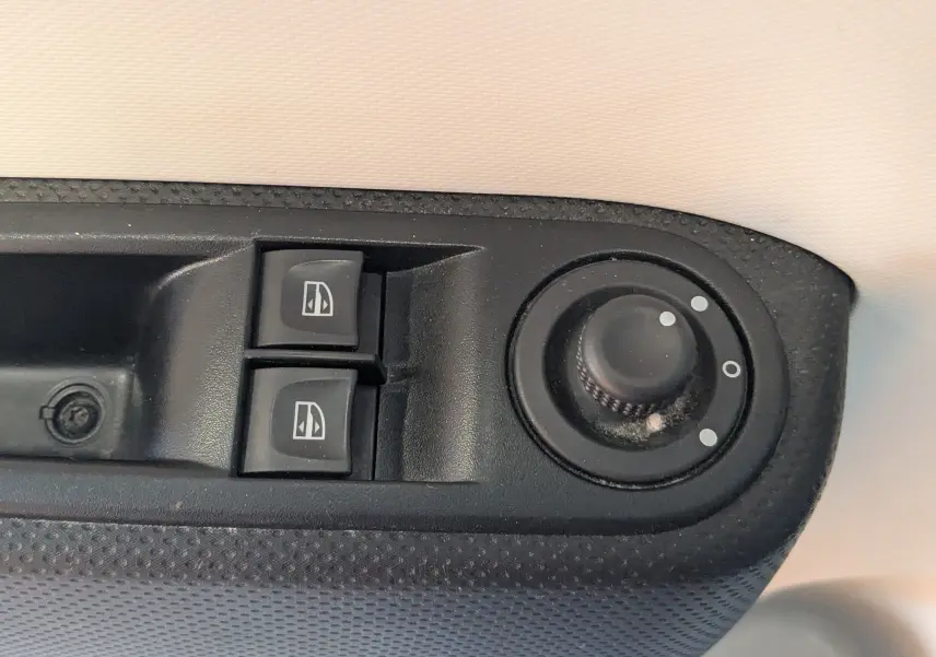 Gros plan sur les commandes de lève-vitres et réglage des rétroviseurs côté conducteur d’une Renault Twingo III gris cassiopée.