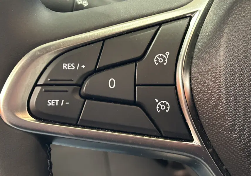 Gros plan sur les commandes de régulateur de vitesse au volant d'une Renault Clio V noire, version BlueDCI 100 Evolution.