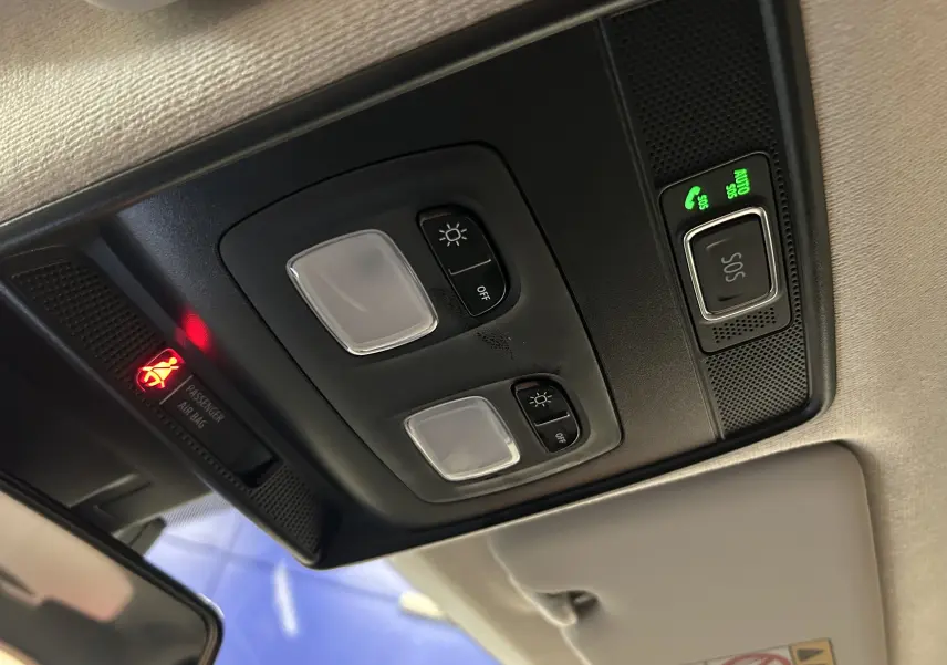 Vue en contre-plongée du plafonnier intérieur noir de la Renault Clio V avec boutons d'éclairage et alerte SOS allumée.