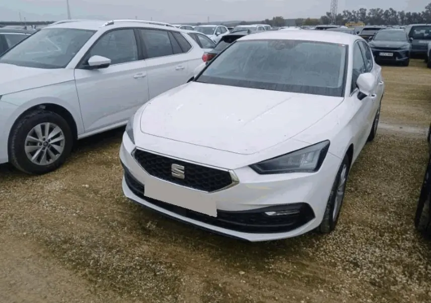 SEAT Leon blanc vue 3/4 avant droite, avec calandre hexagonale et phares LED anguleux sur parking extérieur.
