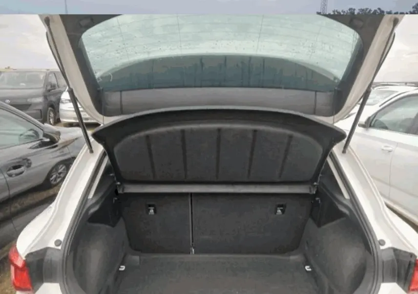 Coffre ouvert vu de l'arrière d'une SEAT Leon blanche, montrant l'espace de chargement vide et les feux arrière.