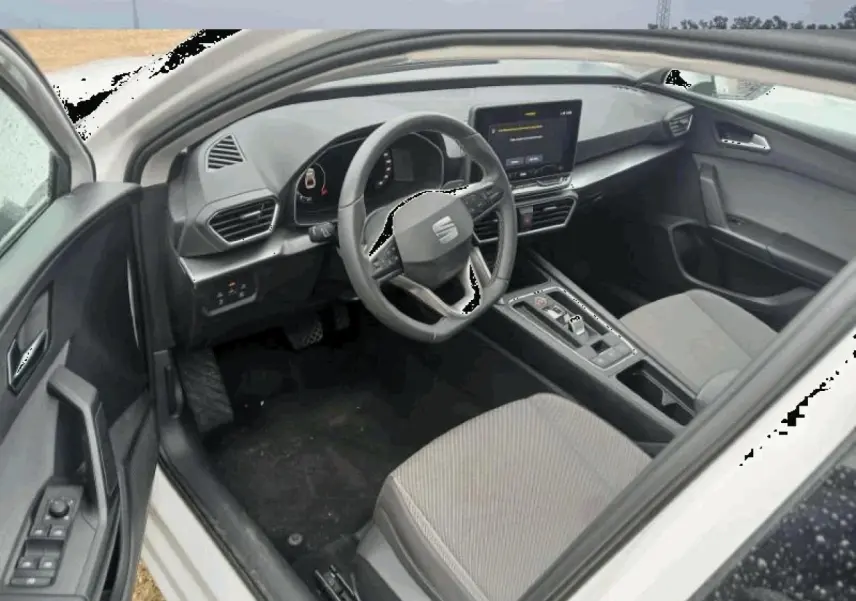 Intérieur de la SEAT Leon 2025 blanc, vue côté conducteur, tableau de bord digital et volant multifonction cuir.