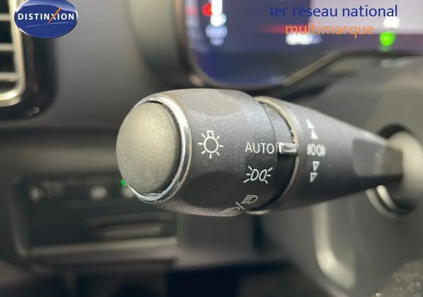 Gros plan sur la commande des feux du Citroën C5 Aircross gris platinium, intérieur avec tableau de bord flou.