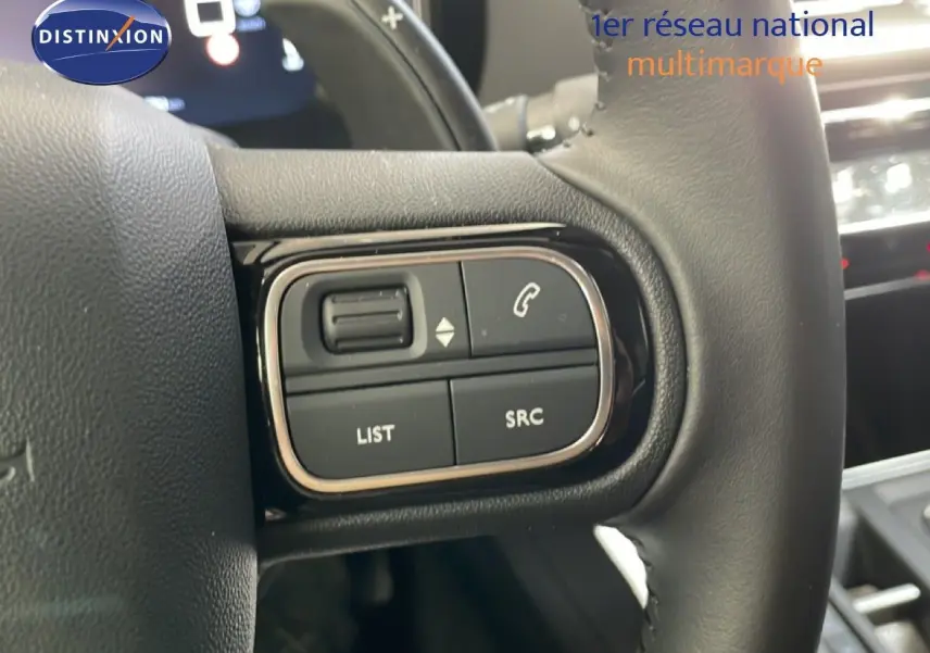 Gros plan sur les commandes gauche du volant du Citroën C5 Aircross 2025, intérieur gris noir avec boutons multifonctions.