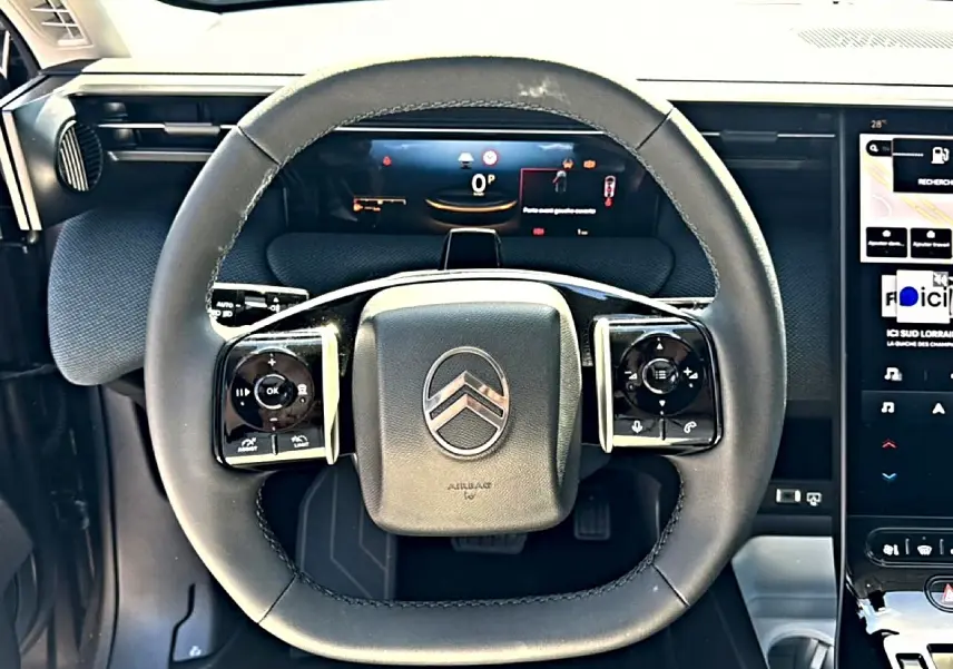 Vue rapprochée du volant multifonction noir du Citroën C5 Aircross 2026 avec tableau de bord numérique et écran tactile.