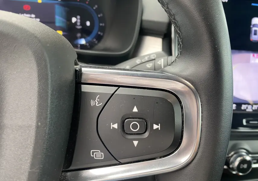Gros plan sur les commandes gauche du volant en cuir noir du Volvo XC40 argent au tableau de bord numérique et écran tactile.
