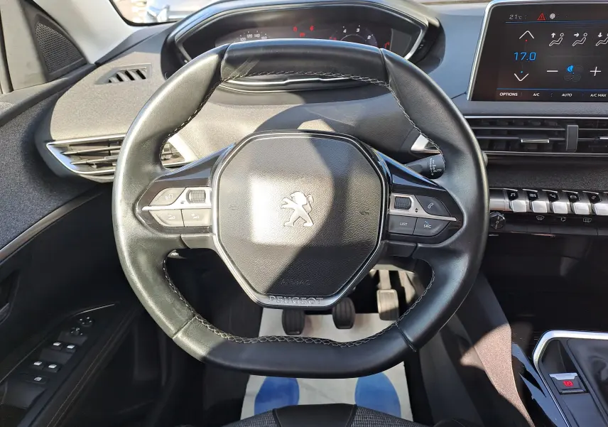 Vue rapprochée du volant cuir noir du Peugeot 3008 2019 avec tableau de bord et écran tactile en arrière-plan.